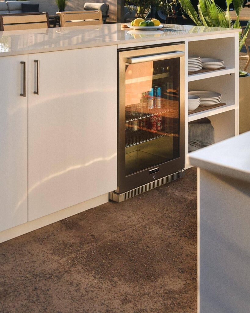 Built-in outdoor refrigerator fitted into cabinetry beneath an outdoor kitchen countertop